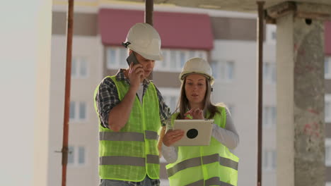 Supervisor-of-a-building-under-construction-man-discussing-with-engineer-designer-woman-the-progress-of-construction-and-examines-a-building-plan.